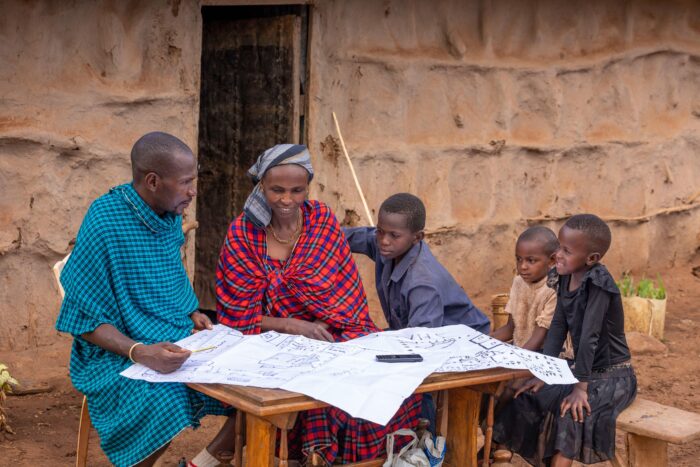 A man, woman and two children sit in front of a table looking at papers